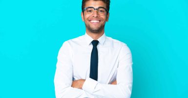Young business Brazilian man isolated on blue background keeping the arms crossed in frontal position